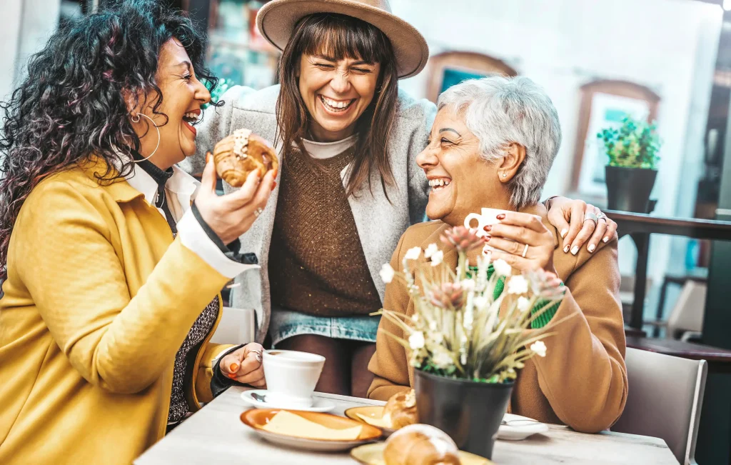 Three women laughing over coffee.